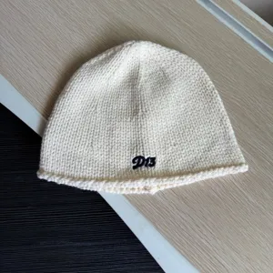 Nahaufnahme Detail einer stilvollen weißen Strickmütze Mütze mit bestickten D13 Buchstaben.