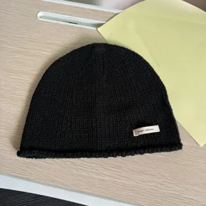 Schwarze Strickmütze Detailaufnahme, lässige Beanie Textur und gewebtes Etikett Nahaufnahme.