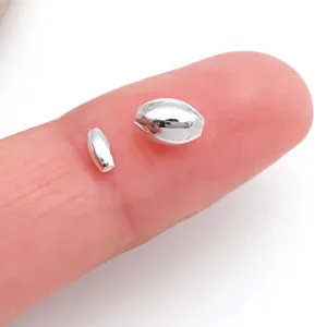Close-up view of silver color metal spacer beads shown on finger for size comparison detail.