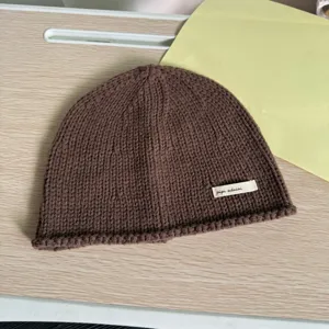 Nahaufnahme Detailansicht einer stylischen braunen Strickmütze mit kleinem Etikett, kuschelig.