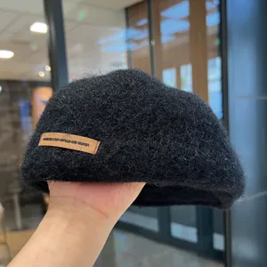 Detailansicht der schwarzen flauschigen Wollmütze, Retro-Malerhut mit stylischem Lederetikett.
