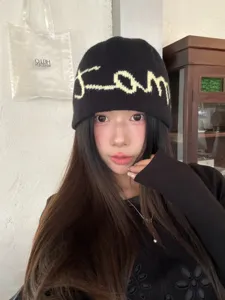 Detail view of Korean style knit beanie, showing soft black fabric texture and cursive text.