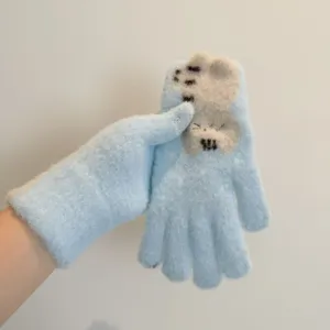 Close-up detail of light blue winter warm knitted touch screen gloves with cute cat design.