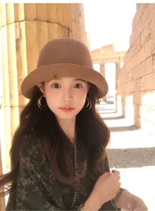Close-up detail of the elegant brown wool bucket hat worn outdoors against ancient ruins.