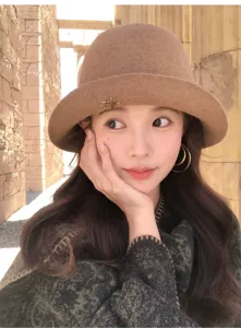 Close-up detail of stylish brown wool bucket hat worn by model outdoors, elegant rolled brim.