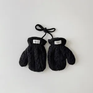 Vue détaillée de mitones tricotées noires pour bébé avec cordon et petite étiquette de marque.