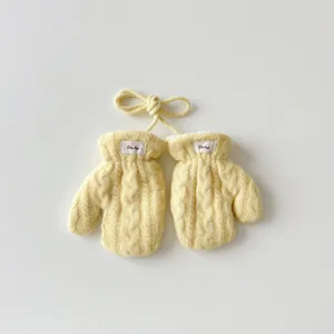 Vue détaillée de mitaines tricotées pour bébé en jaune avec cordon et doublure douce.