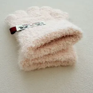 Gros plan de gants roses en polaire douce sans doigts avec une jolie étiquette chat et tricot.