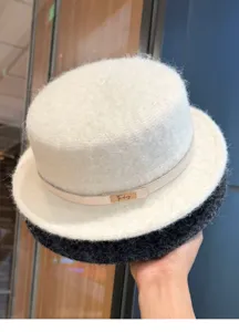 Nahaufnahme des warmen Filz-Plattkopfhutes mit elegantem Lederriemen und Metallschild.