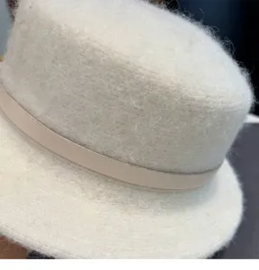 Nahaufnahme einer flauschigen Damen Winter Flachtop Hut mit elegantem beigen Lederriemen.