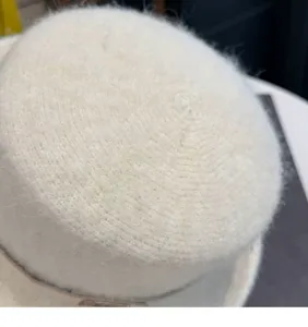 Naheinstellungsdetail der weissen flauschigen Strickhutstruktur mit weicher Wollkrone.