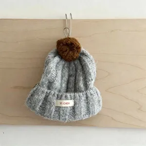 Vue détail bonnet en tricot gris pour enfant avec pompon marron et revers chaud hiver