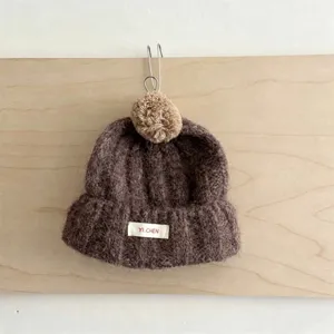 Bonnet en tricot chaud d'hiver pour enfants avec joli pompon et revers, marron confortable.