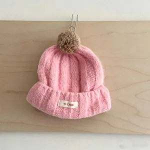 Gros plan détaillé d'un joli bonnet d'hiver en tricot rose pour enfant avec pompon.