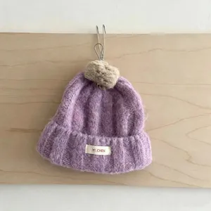 Détail bonnet tricoté enfant, bonnet chaud d'hiver violet avec pompon et bord roulé.