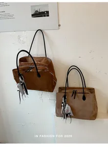 Gedetailleerd overzicht van de retro bruine suède shopper tas met zwart handvat en hanger.