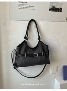 Detail van donkergrijze krijtstreep tas met lederen handvatten en decoratieve riem.