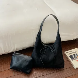 Gedetailleerd overzicht van de zwarte suède schoudertas met een elegante strik en pouch.
