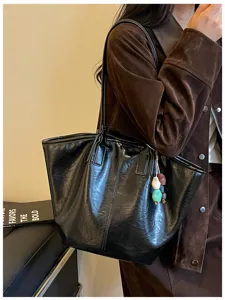 Gedetailleerd overzicht van de zwarte lederen tote tas met elegante schouderband en chique hanger.