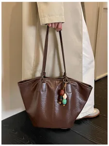 Bruine shopper tas detail met grote capaciteit en een prachtig decoratieve kralen hanger.