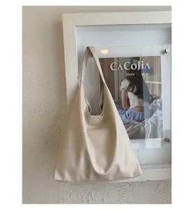 Gedetailleerd uitzicht van de zachte PU lederen schoudertas hangend aan een beige muur.