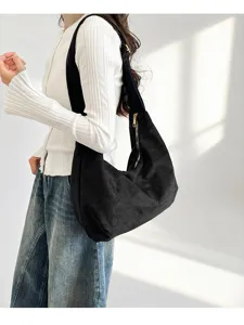 Detailansicht der schwarzen Wildleder-Hobo-Tasche über der Schulter, weiche Textur und Design.