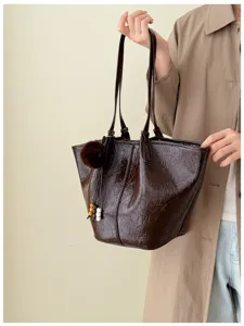 Detail view of retro oil-wax leather tote shoulder bag with chic pom-pom charm for women.