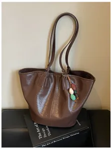Gedetailleerd overzicht van de vintage bruine PU lederen tote tas met dubbele hengsels en bedel.
