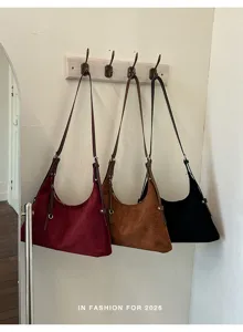 Gedetailleerd overzicht van retro suède schoudertassen netjes opgehangen aan een houten haak.