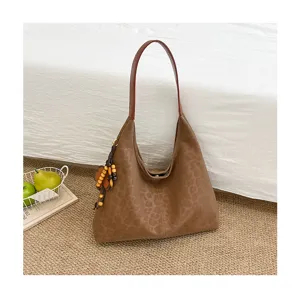 Detailansicht der braunen Damen Schultertasche mit Leo-Muster in gemütlichem Schlafzimmer.