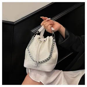 Detailopname van de witte slangenleer emmertas met zilveren ketting en koord sluiting.