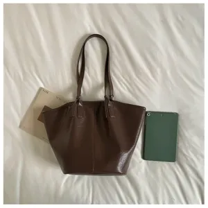 Gedetailleerd overzicht van de vintage bruine tas met accessoires op een wit bed.