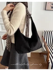 Detailopname van een zwarte suède schoudertas gedragen bij een vintage outfit.