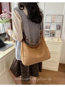 Gedetailleerd overzicht van bruine suède schoudertas, slappe hobo-stijl met elegante knoopband.