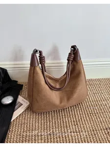 Gedetailleerd overzicht van bruine suède schoudertas met stijlvol geknoopt handvat in vintage setting.