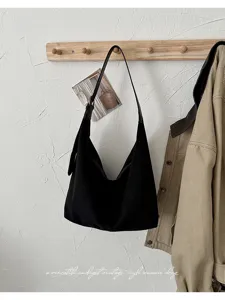 Gedetailleerd overzicht van zwarte suède hobo schoudertas hangend aan houten muurhaak.