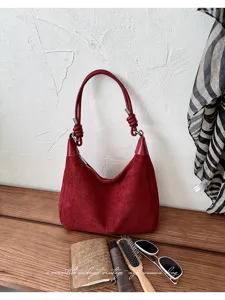 Elegante suède schoudertas voor dames met chique geknoopt handvat en ruim interieur voor dagelijks gebruik.