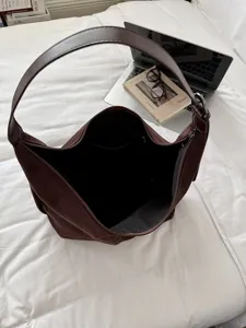Gedetailleerd uitzicht op het interieur en de ruime capaciteit van de bruine suède schoudertas.