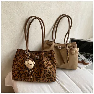 Detail van de retro suède luipaard tote tas met grote capaciteit en schattige berenhanger.