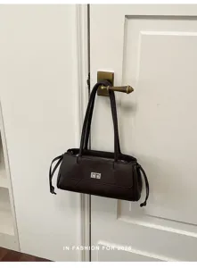 Detailopname van een donkerbruine gewatteerde retro schoudertas met metalen draaisluiting.