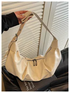 Close-up van de stijlvolle beige leren schoudertas, met een zachte en casual knoedelvorm.