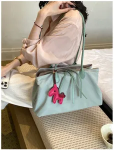 Detailopname van lichte nylon tas met schattige paardenhanger en handige vakken.