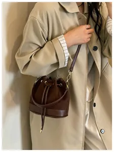 Detailopname van de donkerbruine vintage suède bucket bag met trekkoordsluiting en metalen beslag.