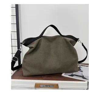 Gedetailleerd overzicht van grote canvas tote tas met zwarte handvatten en verstelbare riem.