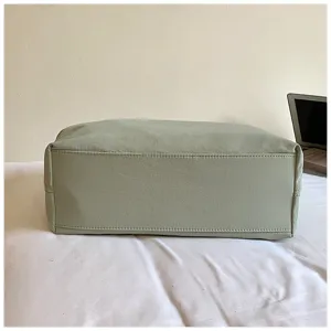 Gedetailleerd overzicht van de bodem van de saliegroene PU lederen tote tas met stiksels.