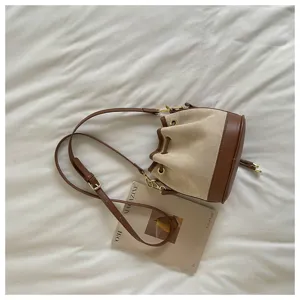 Retro canvas en lederen emmertas detailopname met verstelbare riem en metalen accessoires.