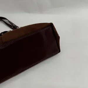 Detailopname van de donkerbruine suède schoudertas onderkant en fijne stiksels.