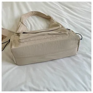 Vista dettagliata della borsa a spalla in nylon beige casual, design minimalista per ufficio.
