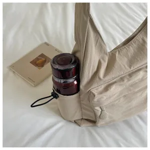 Dettaglio della borsa a spalla casual beige con tasca laterale e tasca frontale con zip.