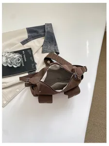 Gedetailleerd overzicht van vintage bruine canvas schoudertas met klinknagelriem en binnenvoering.